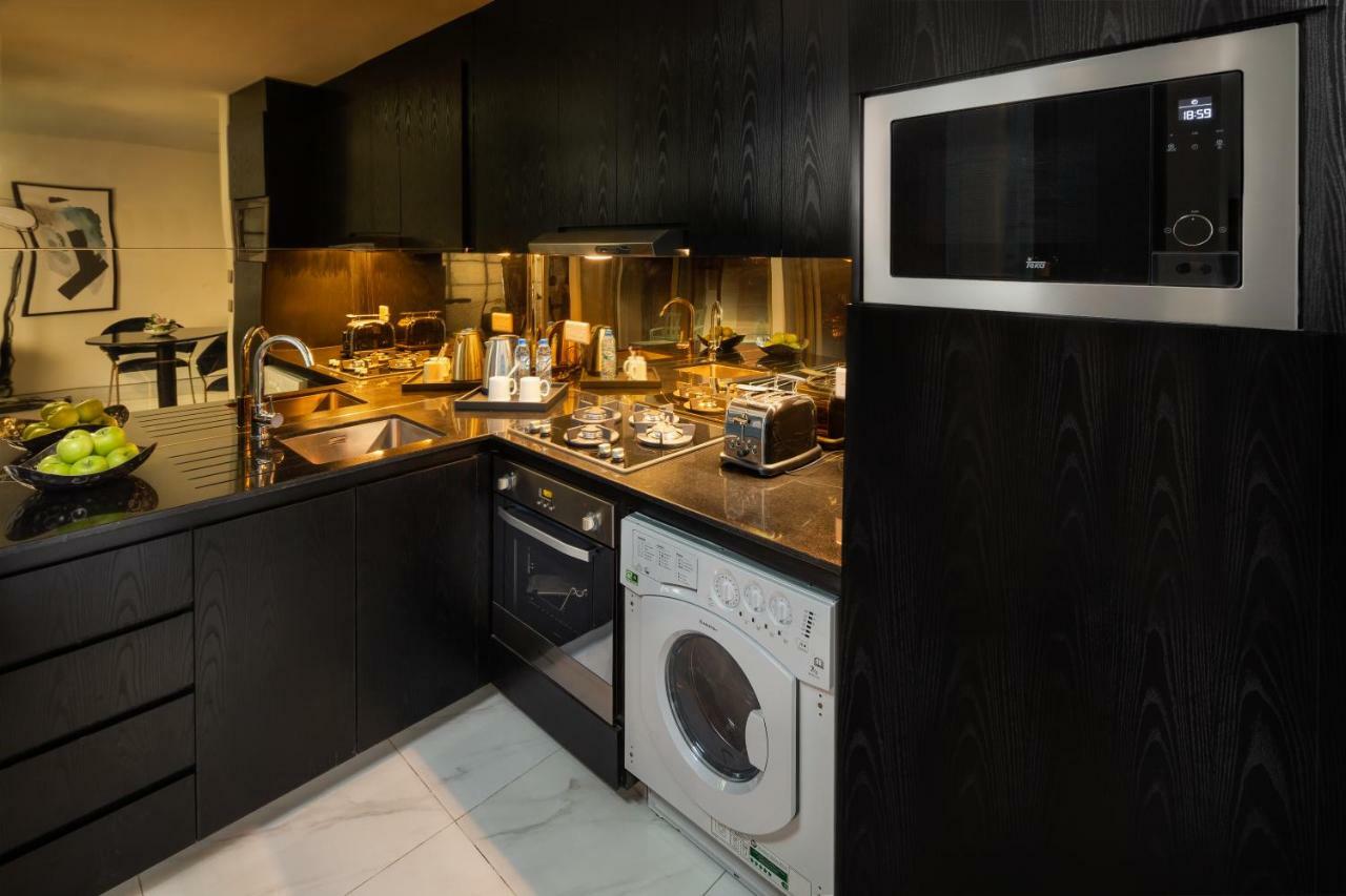 Aparthotel Millennium Atria Business Bay Dubaj Exteriér fotografie The photo shows a modern kitchen with a sleek design. The cabinets and surfaces are predominantly black, creating a contemporary look. There is a stainless steel microwave mounted above the countertop, and on the counter, various kitchen appliances l